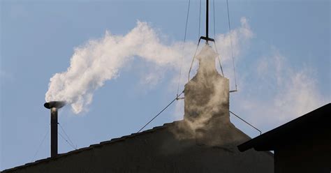 Ilustračná fotografia domu s viditeľnou parou vychádzajúcou z komína v jesennom prostredí