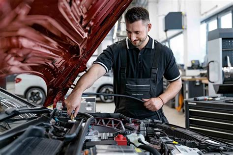 Mechanik s diagnostickým prístrojom pripnutým ku klimatizačnému systému automobilu