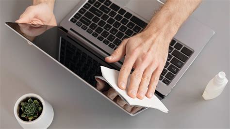 Osoba čistiaca displej notebooku mikrovláknovou handričkou